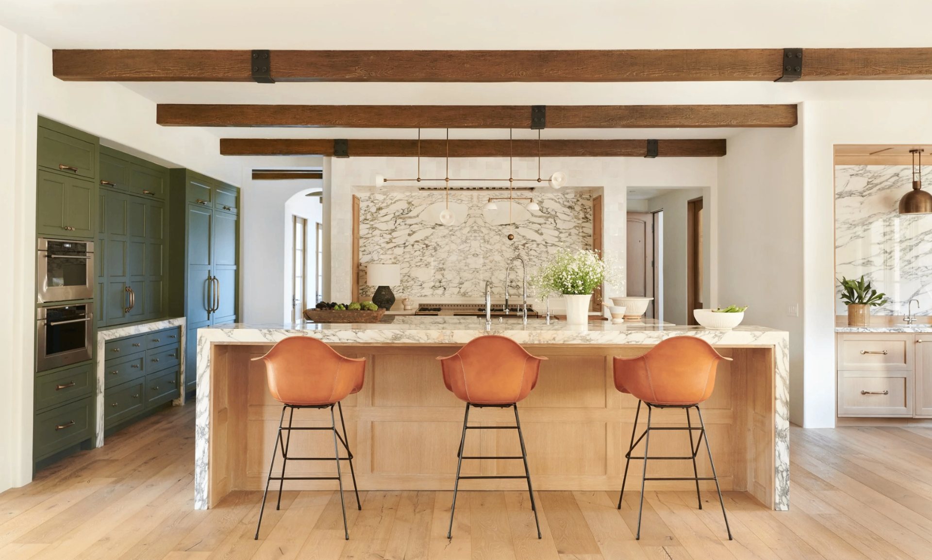 Malibu kitchen with marble island, exposed wood beams, and leather counter stools, as featured in House Beautiful — by Tammy Randall Wood / Interior Archaeology