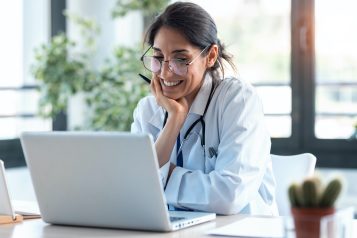 Shot,Of,Smiling,Female,Doctor,Working,With,Her,Laptop,In