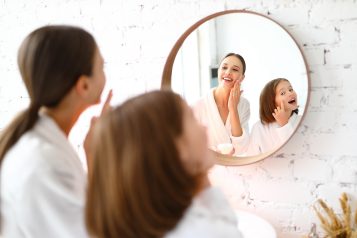 Happy,Young,Woman,With,Preteen,Daughter,Standing,Near,Mirror,And