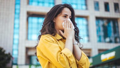 girl sneezing while put cloth on nose