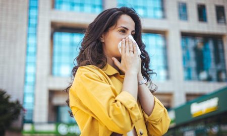 girl sneezing while put cloth on nose
