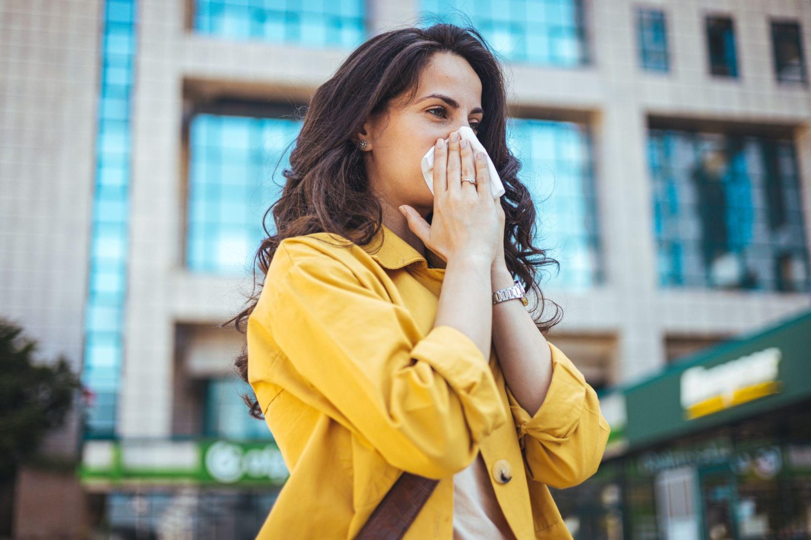 girl sneezing while put cloth on nose