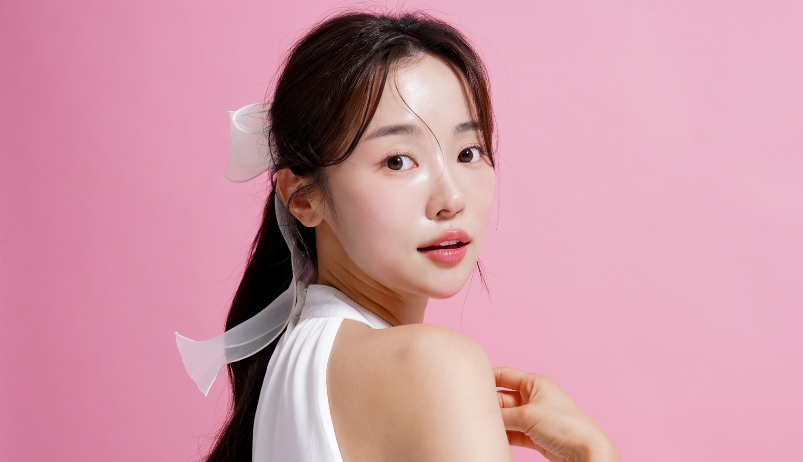 light beauty portrait of a young Asian woman shot against a pink background