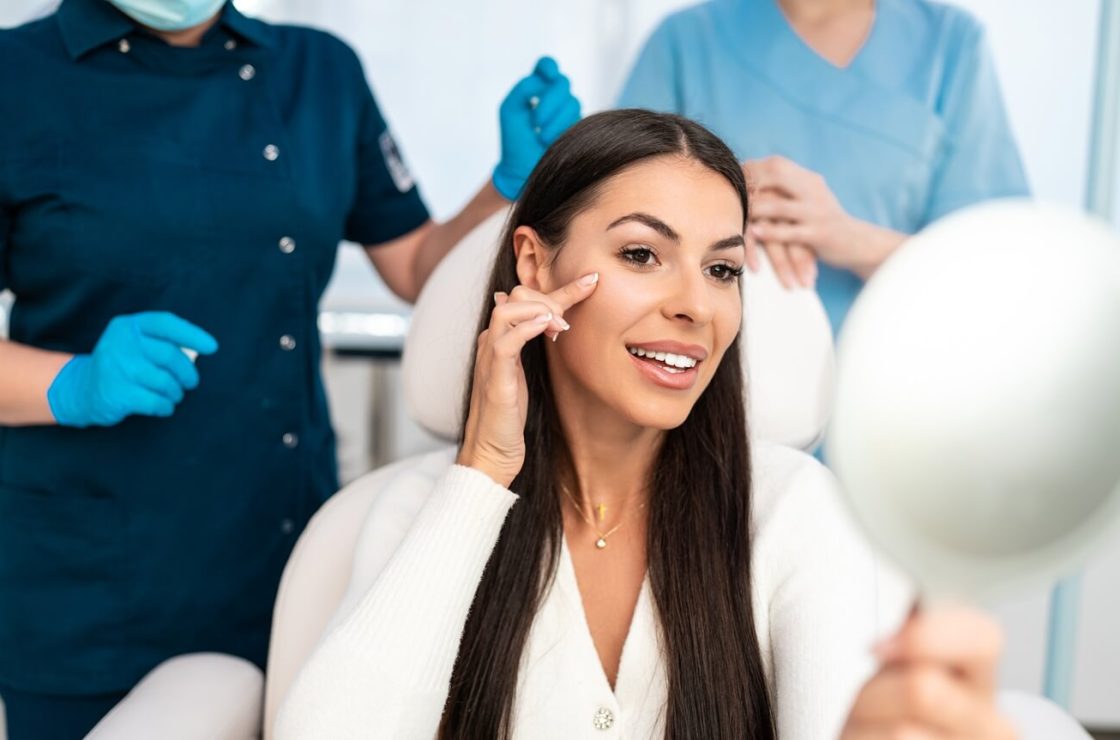 beautiful and happy young woman sitting in medical chair and looking in the mirror