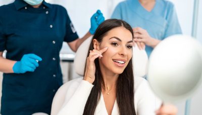 beautiful and happy young woman sitting in medical chair and looking in the mirror