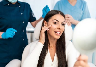 beautiful and happy young woman sitting in medical chair and looking in the mirror
