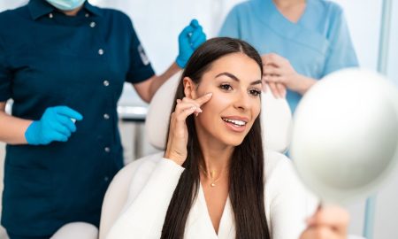 beautiful and happy young woman sitting in medical chair and looking in the mirror
