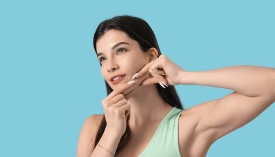 beautiful young woman doing face building exercise on blue background - Jawline contouring