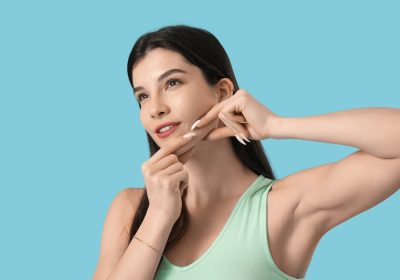 beautiful young woman doing face building exercise on blue background - Jawline contouring