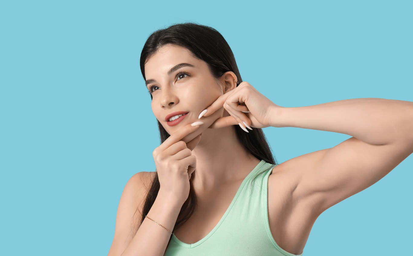 beautiful young woman doing face building exercise on blue background