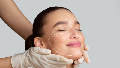 calm girl receiving face massage from cosmetologist who wearing protective gloves, isolated