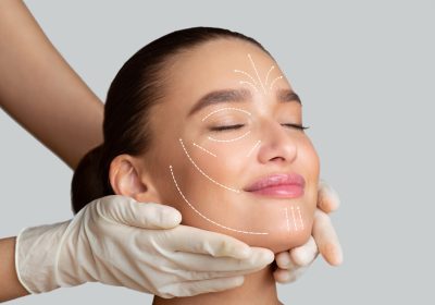 calm girl receiving face massage from cosmetologist who wearing protective gloves, isolated