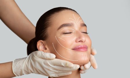 calm girl receiving face massage from cosmetologist who wearing protective gloves, isolated
