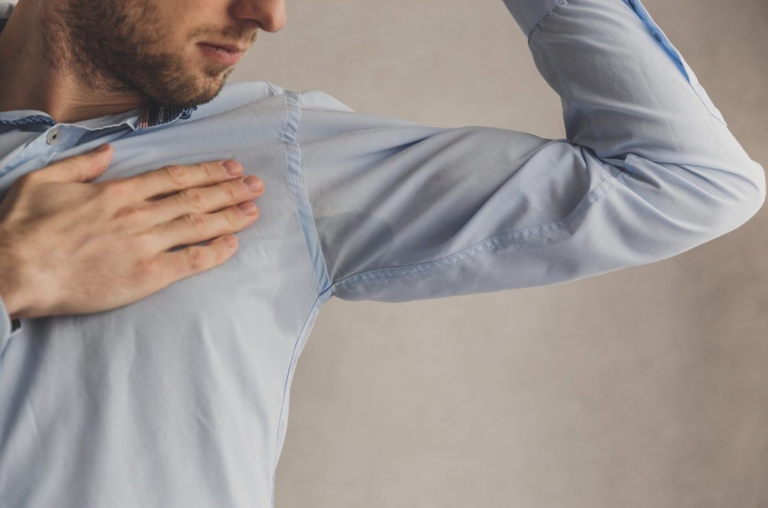 men checking his underarms for sweating