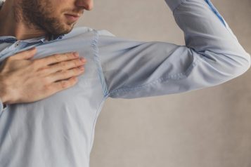 men checking his underarms for sweating