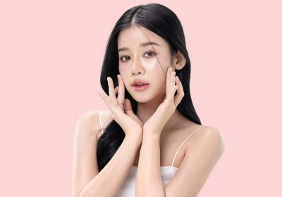 glowing skin make up style of beautiful young Asian model isolated on pink background