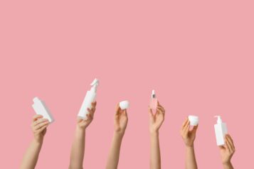 Female,Hands,With,Bottles,And,Jars,Of,Cosmetic,Products,On