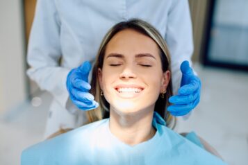 Happy,Patient,With,White,Teeth,Receiving,Dental,Examination,From,Dentist,