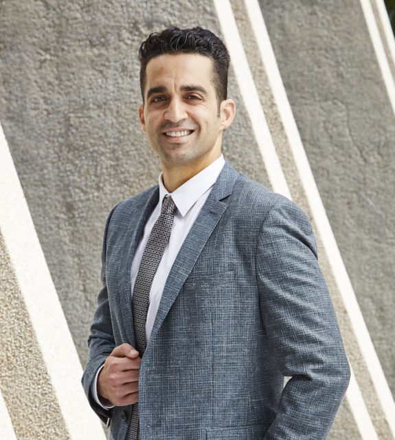 A personal injury lawyer in a suit and tie stands confidently in front of a professional building in Los Angeles, California.