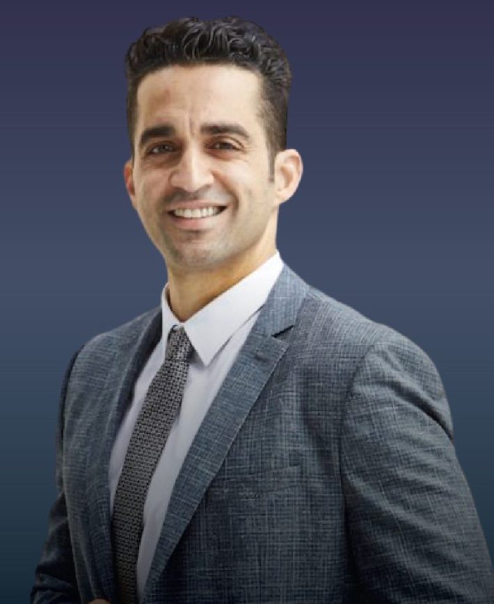 A personal injury lawyer in a suit and tie stands confidently in front of a professional building in Los Angeles, California.