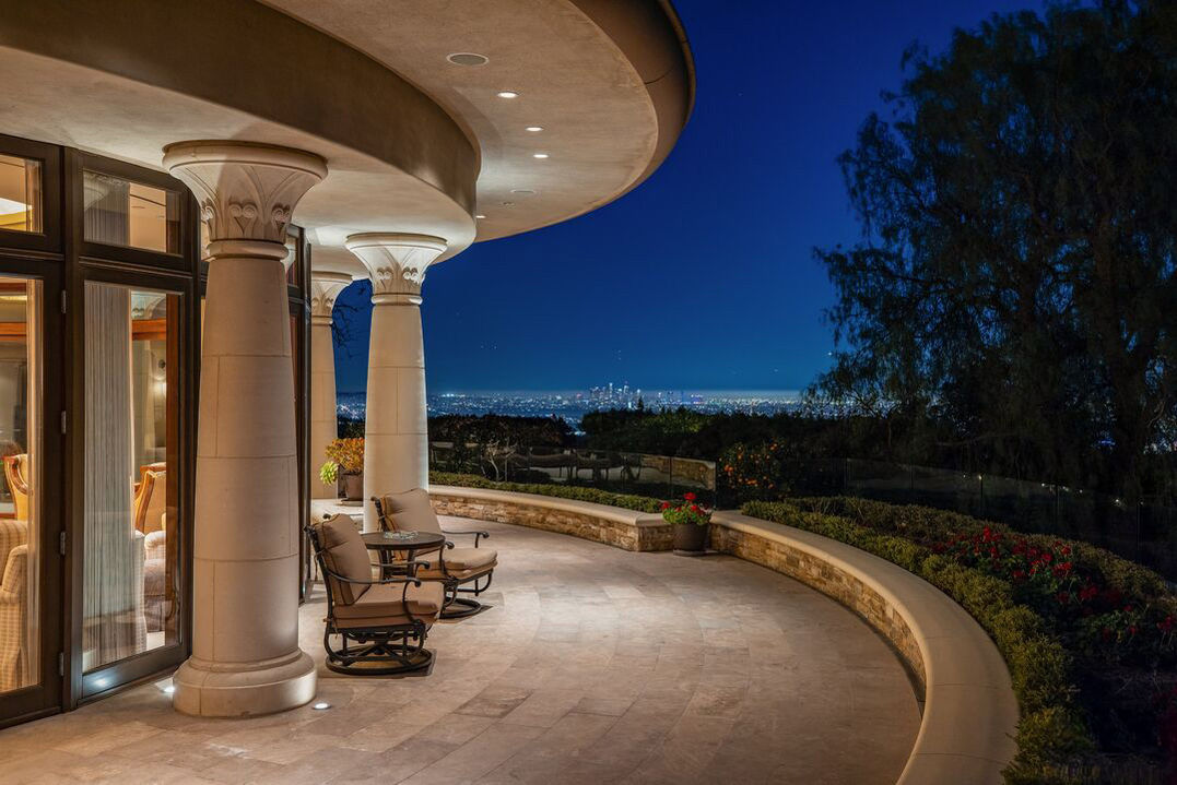 Curved covered terrace at dusk overlooking a city skyline