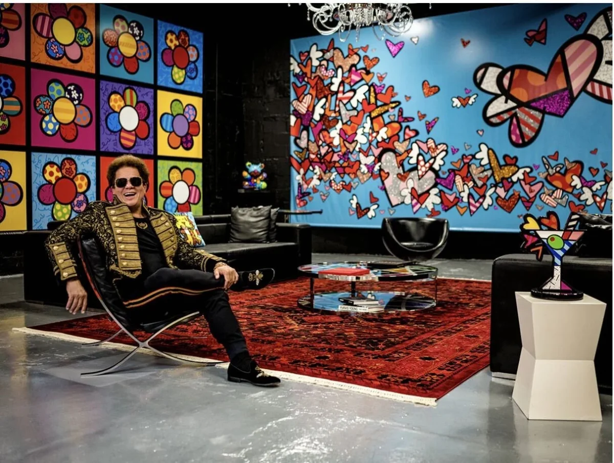 Romero Britto seated among his artworks in his studio