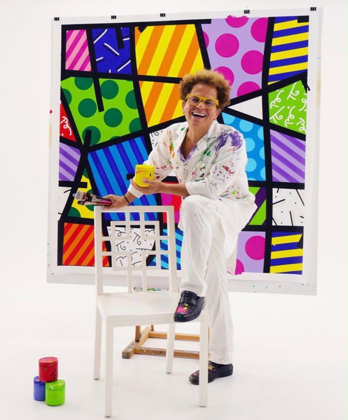 Romero Britto painting in his studio in front of a colorful geometric artwork