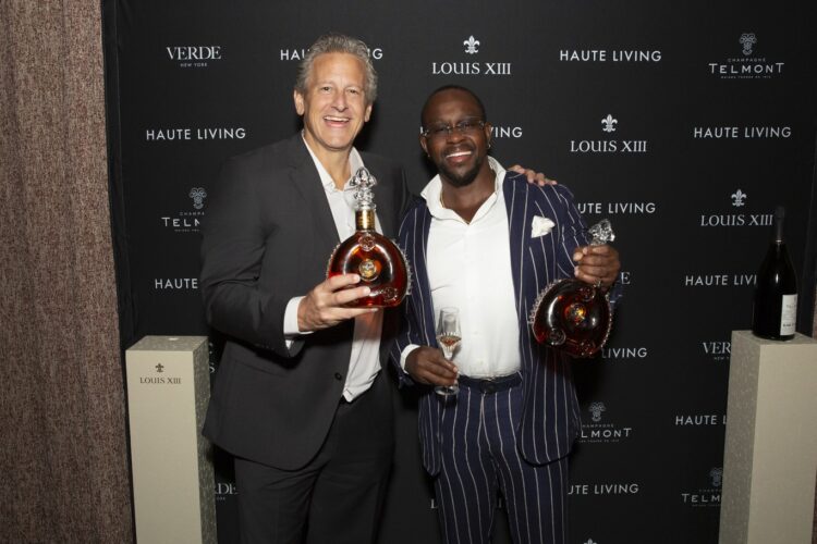 Dr. Daniel Beyda and Peter Gordan holding Louis XIII decanters at the Haute Living step-and-repeat