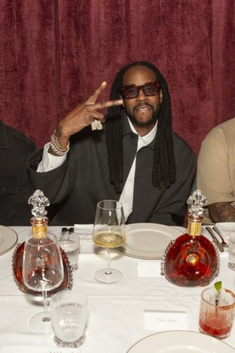 2 Chainz seated at the dinner table with Louis XIII decanters