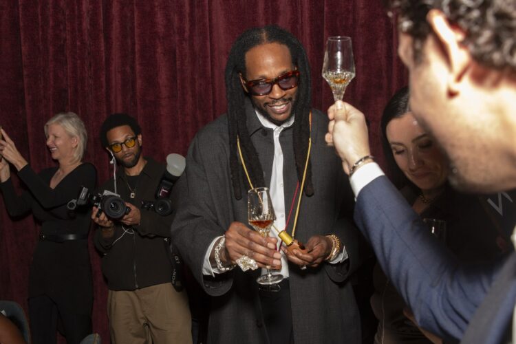 2 Chainz raising a glass with Louis XIII’s Justine Nicolas at the Haute Living dinner at Verde New York