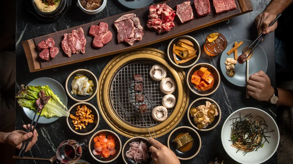 COTE Korean steakhouse grill table with raw cuts of beef and banchan, among the best steakhouses in NYC