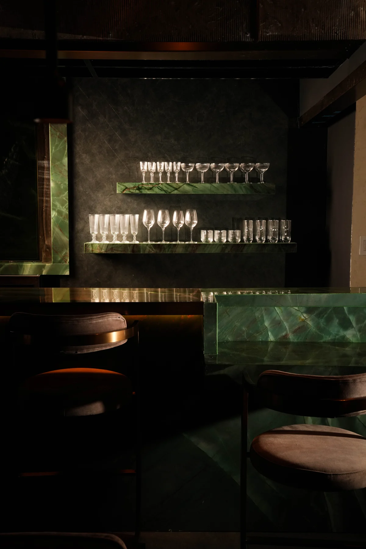 Glassware on green stone shelves above the bar at A Pasta Bar Miami Beach