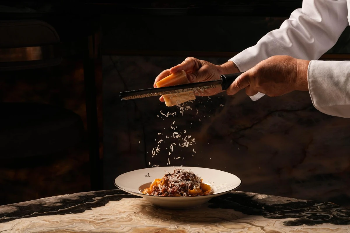 Cheese is grated over a bowl of pasta at the table at A Pasta Bar Miami Beach