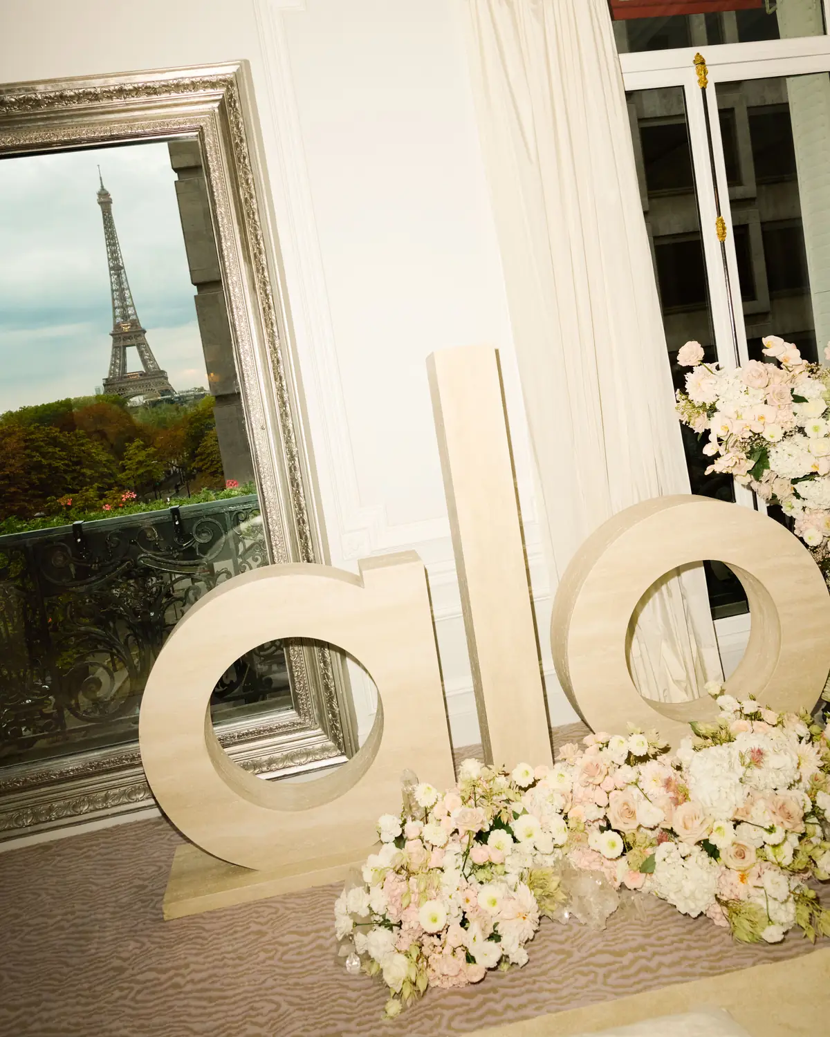 Oversize ALO letters and blush flowers in front of a mirror reflecting the Eiffel Tower at the ALO Plaza Athénée Paris Fashion Week takeover