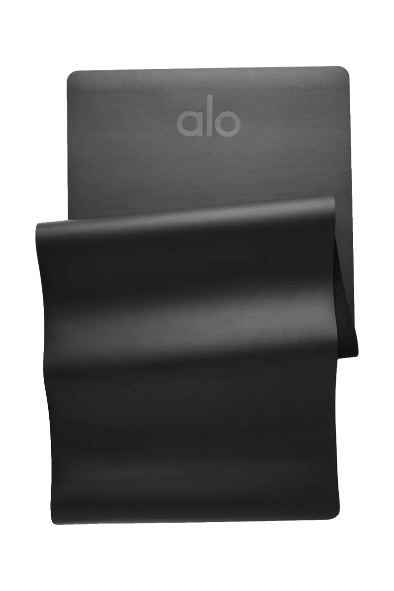 The black ALO Warrior Mat partly unrolled on a white background, a pick inspired by the ALO Plaza Athénée takeover