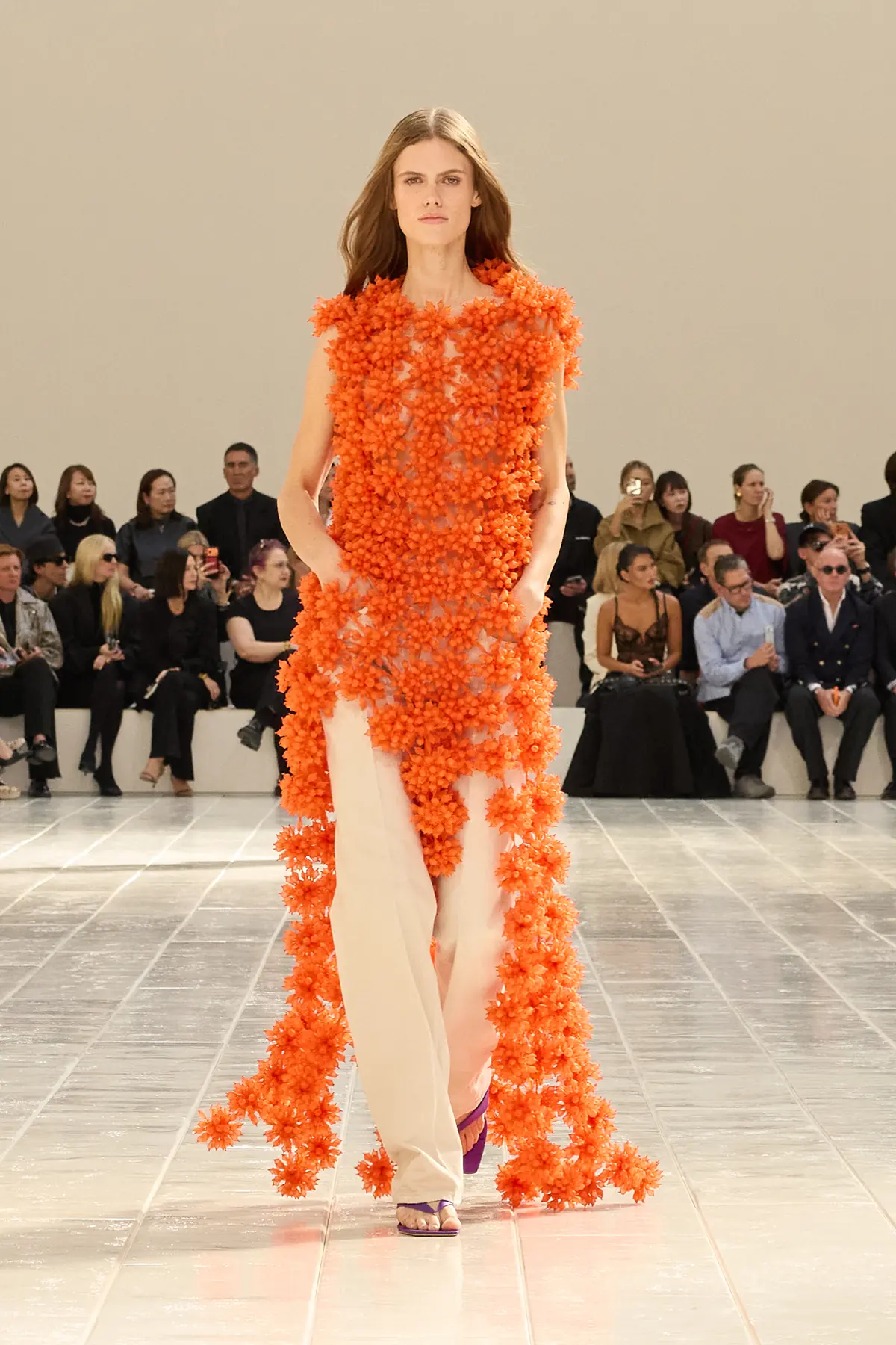 Model in a look covered in clustered orange flowers over cream trousers in Balenciaga Summer 2027 Look 21