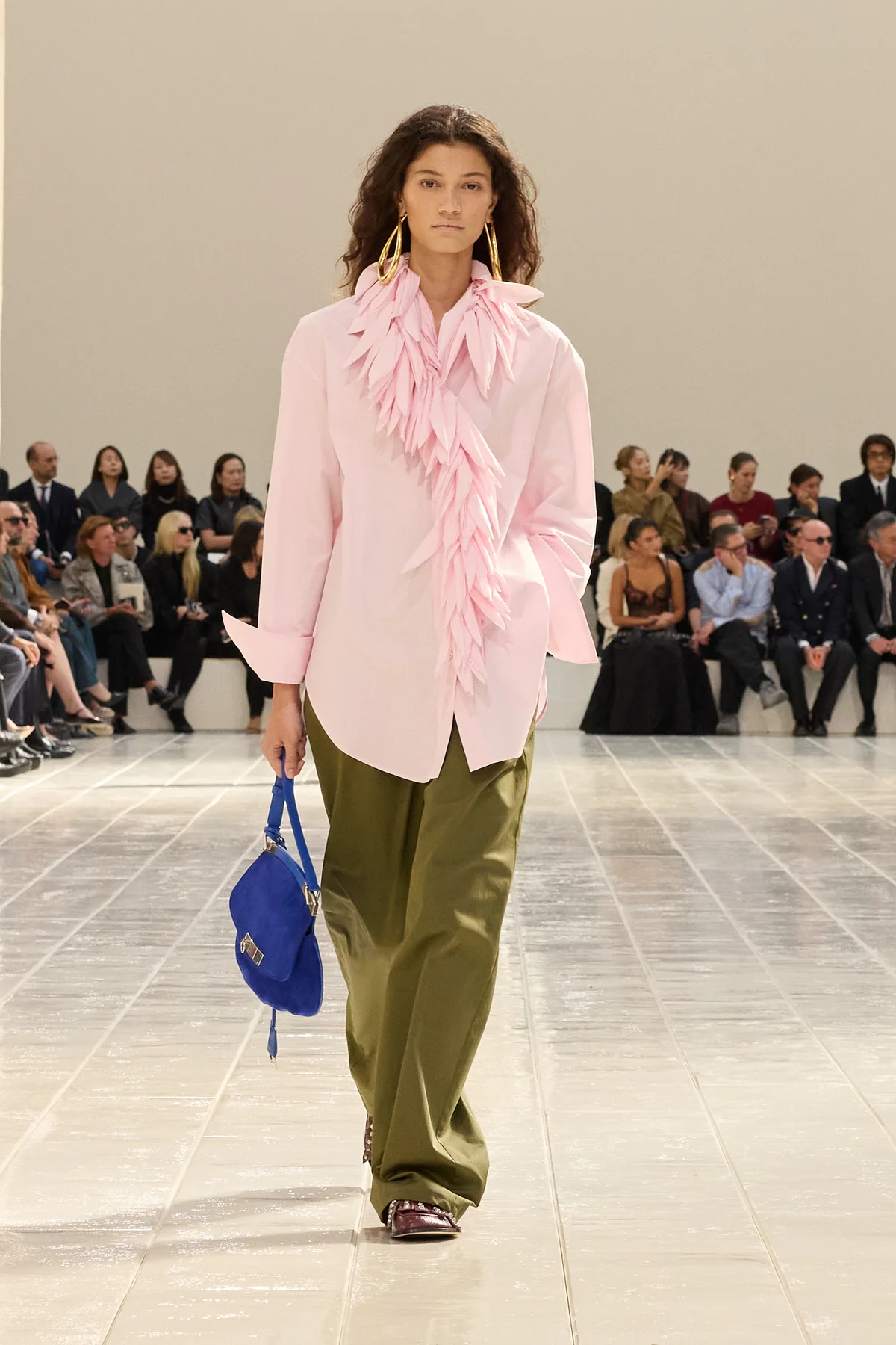 Model in a pale pink shirt with a tendril-trimmed collar, olive trousers and a cobalt blue bag in Balenciaga Summer 2027 Look 42