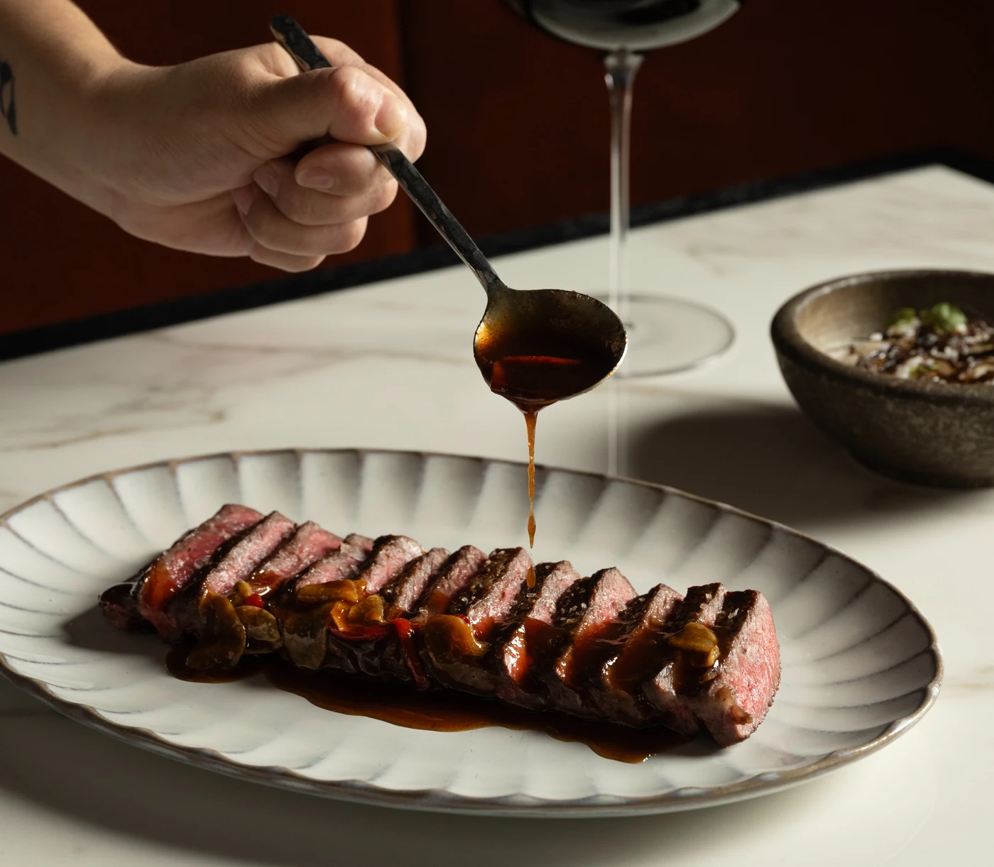 Sliced medium-rare steak being finished with a dark mushroom jus at Bazaar Meat Miami Beach