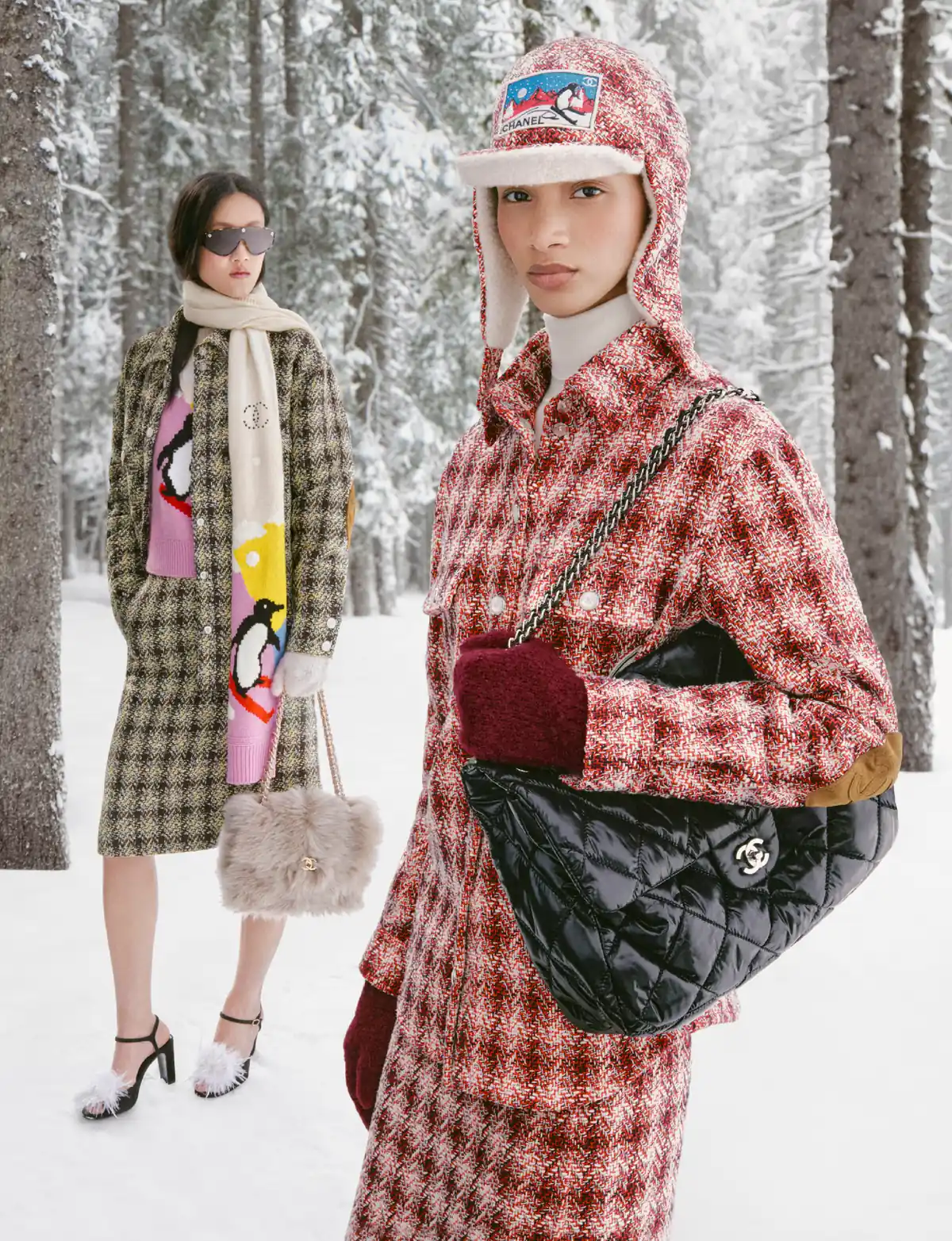 Two models in Chanel check tweeds among snowy pines, one carrying a black quilted Chanel bag, Chanel Coco Neige 2026/27