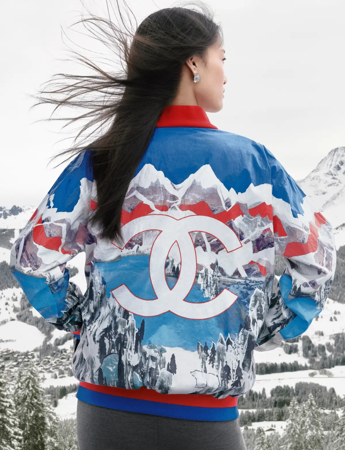 Back view of a model in a Chanel Coco Neige 2026/27 jacket printed with snowy mountains and an oversized CC logo