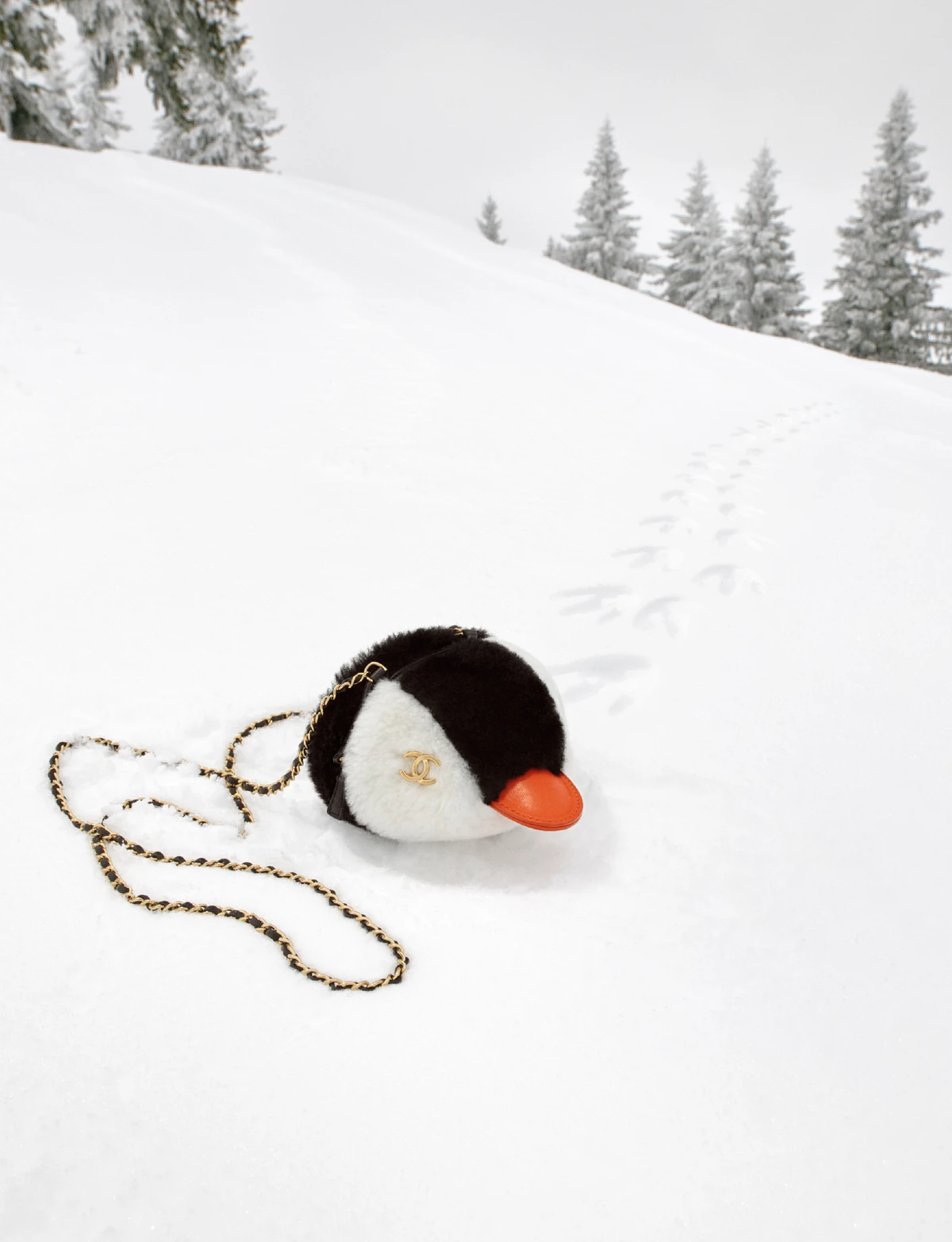 Chanel Coco Neige 2026/27 penguin bag with a gold chain strap resting in the snow