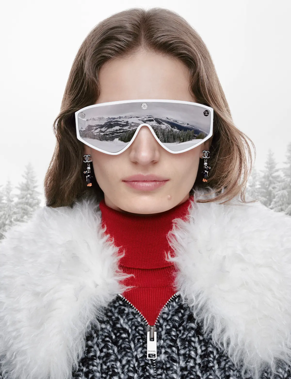 Close-up of a model in white shield ski goggles, a red knit and a white shearling collar in the Chanel Coco Neige 2026/27 campaign