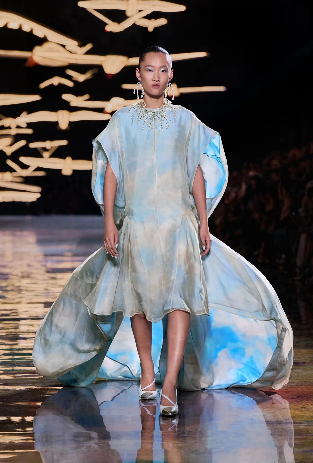 A cloud-printed silk caped dress with a billowing train and pearl collar at Chanel Spring Summer 2027