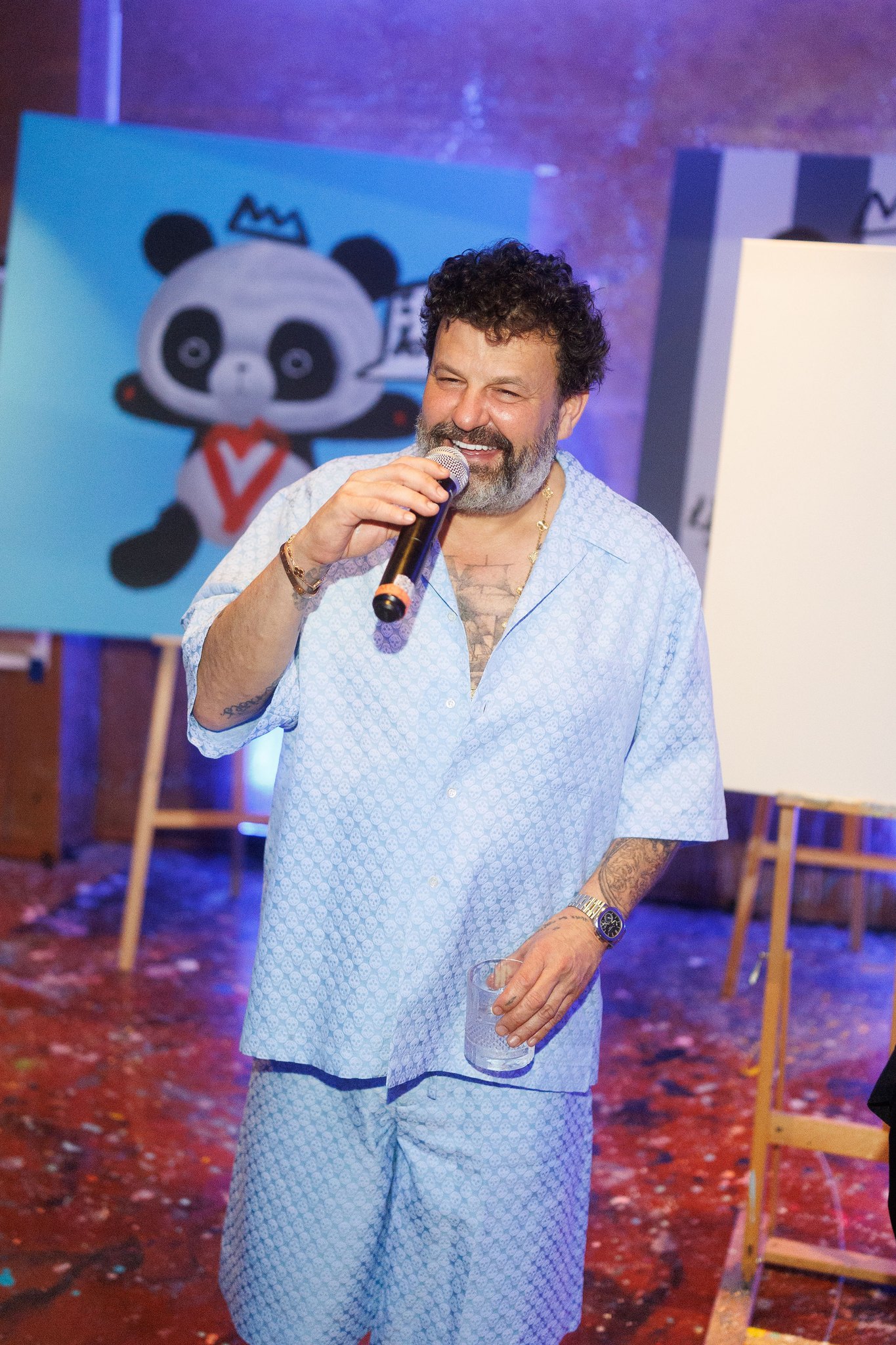 Domingo Zapata speaking into a microphone beside a panda painting on an easel