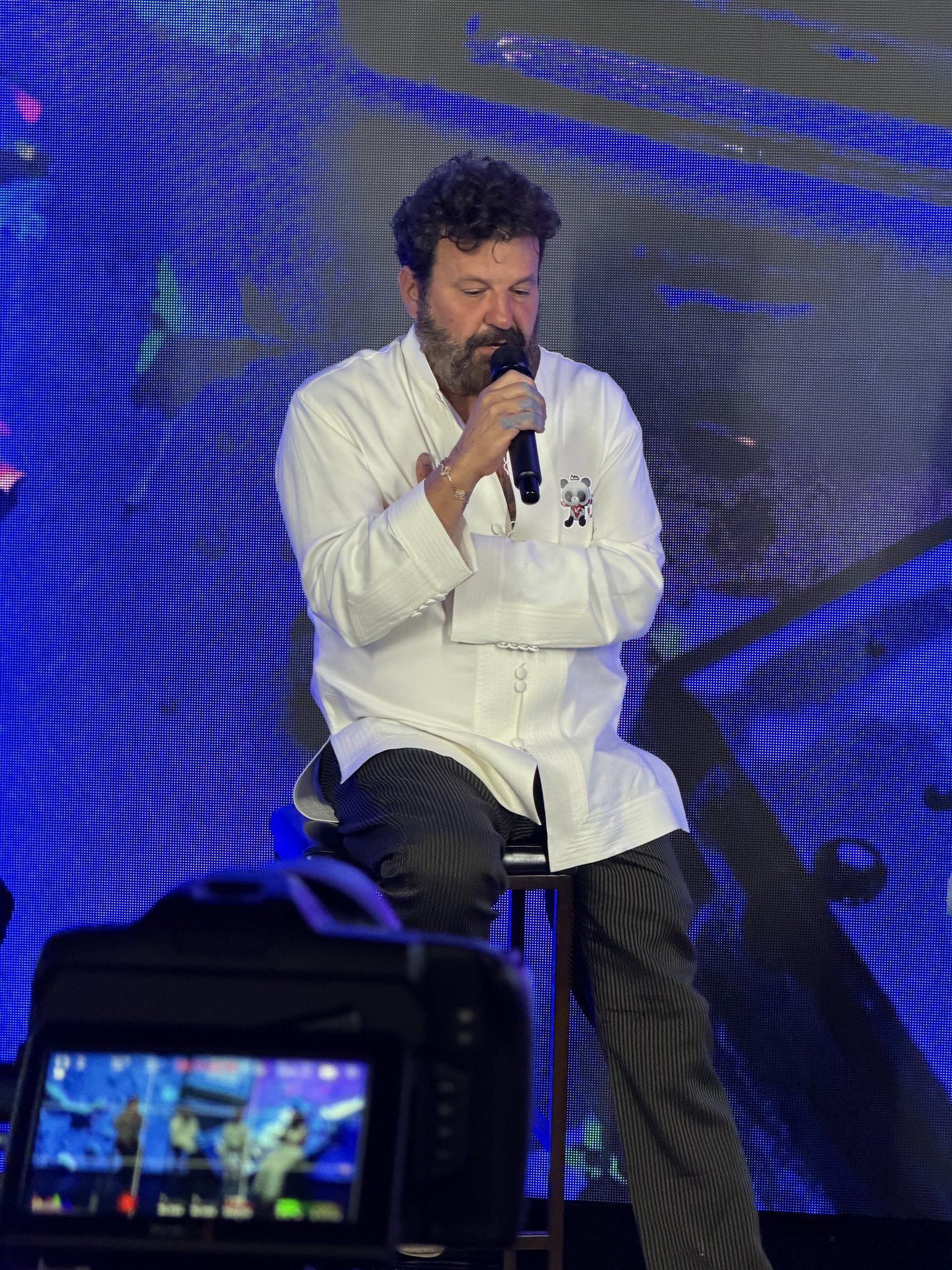 Domingo Zapata seated on stage, speaking into a microphone