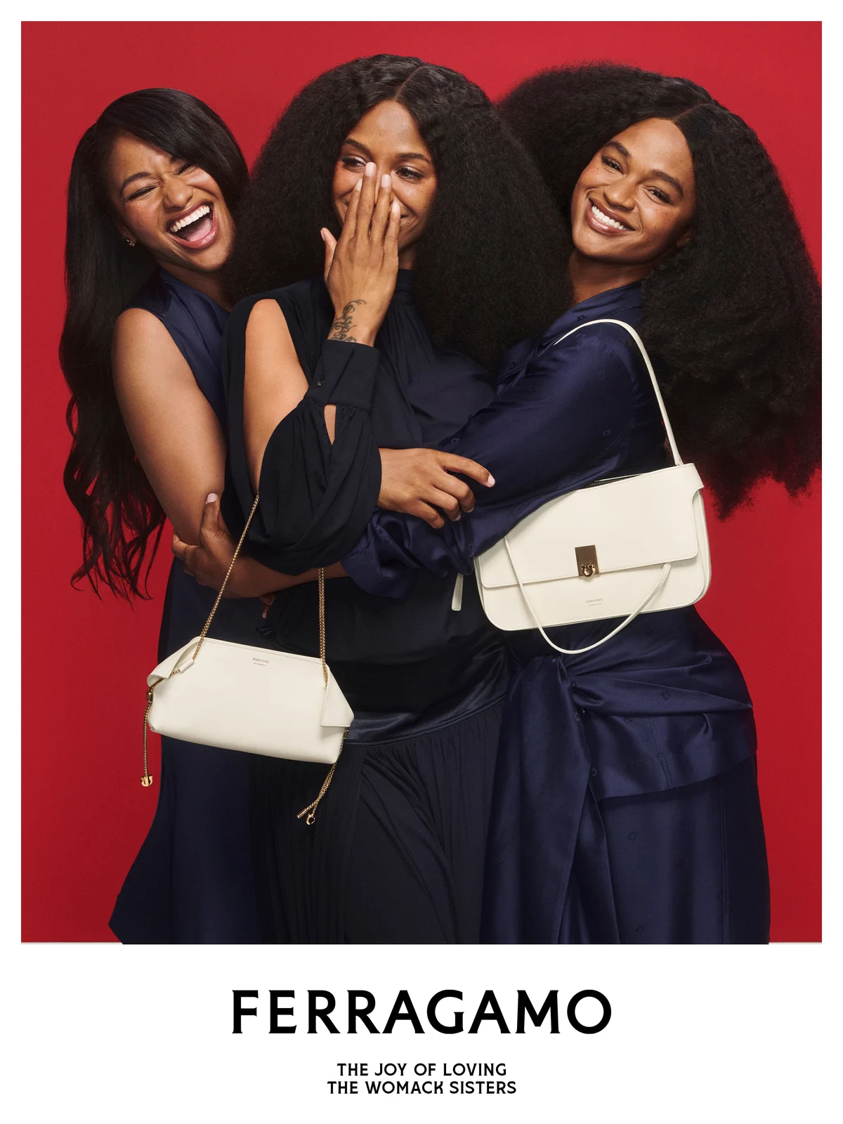 The Womack Sisters laughing together in navy with cream Ferragamo bags in the Ferragamo holiday campaign