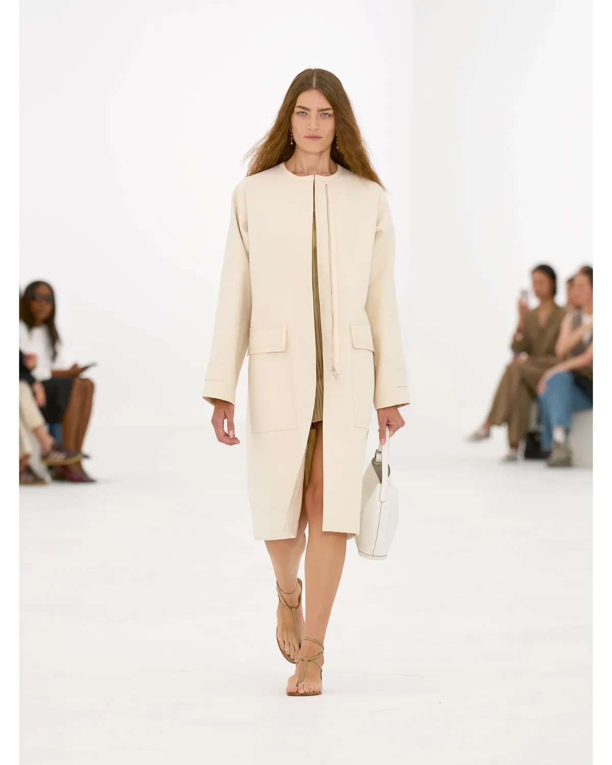 Hermès Spring/Summer 2027 Look 4, a collarless cream coat over a fine knit dress, at Paris Fashion Week