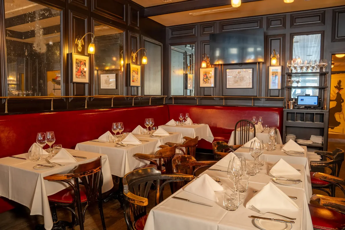 Red banquettes and white tablecloths in the dining room at La Goulue, a French date night restaurant in Palm Beach