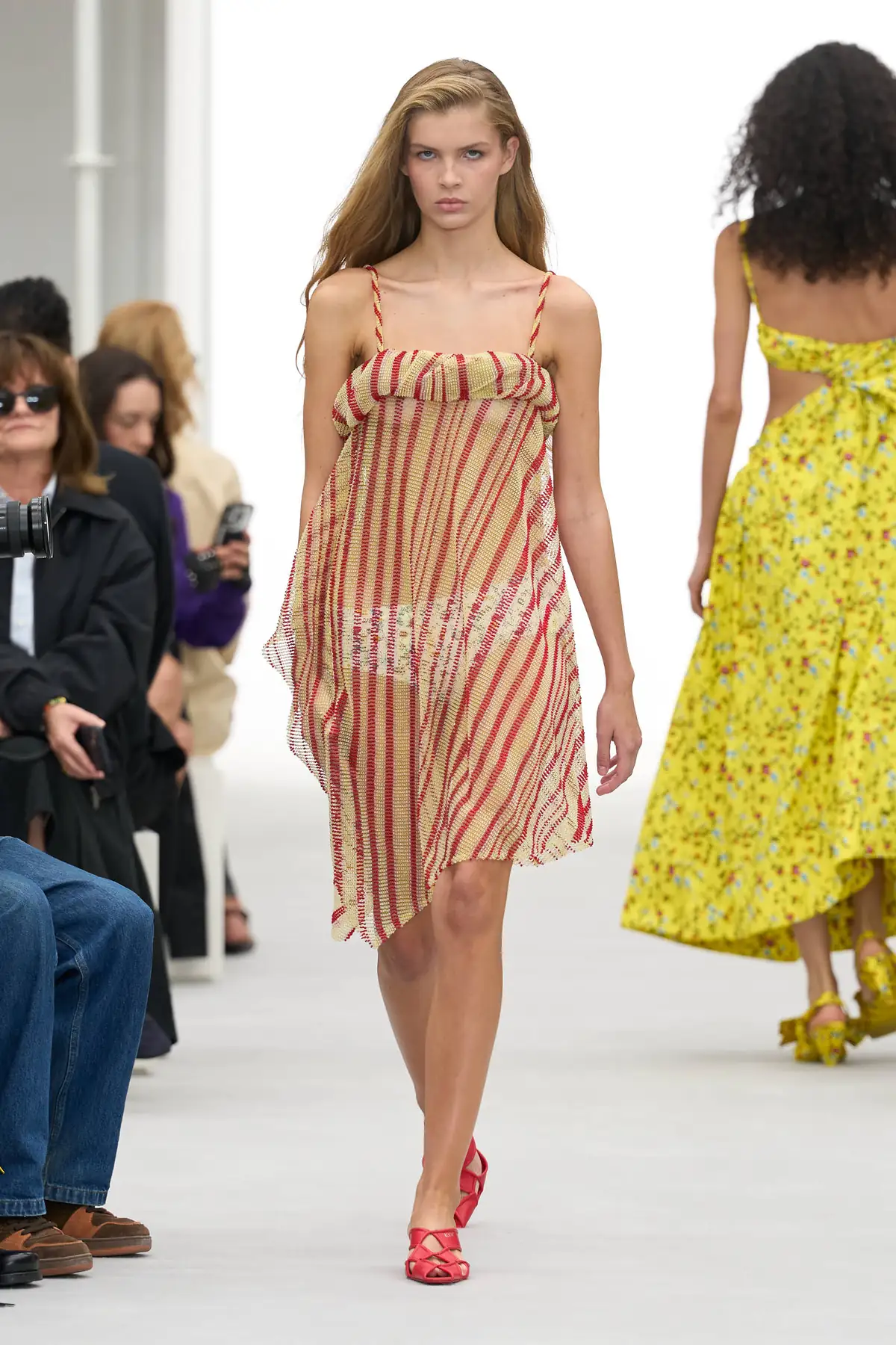 Model in a sheer coral and sand striped slip dress and red sandals at the Loewe Spring Summer 2027 show