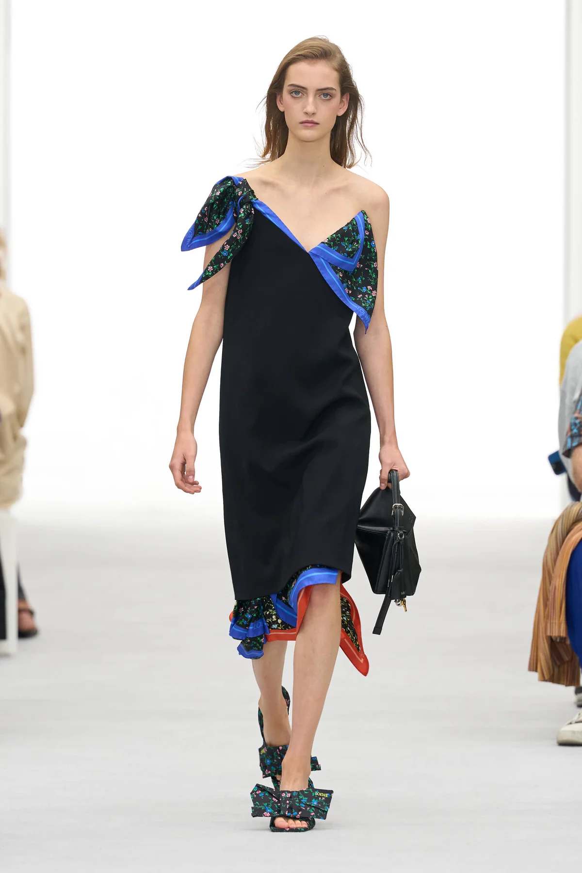 Model in a black slip dress with cobalt-edged floral panels at the neckline and hem at the Loewe Spring Summer 2027 show